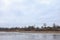 Riverside view of river flowing near countryside city with trees on winter