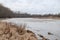 Riverside view of river flowing near countryside city with trees on winter