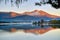 The riverside village and mountains reflect the water in the misty morning at Lake Wolfgang