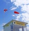 RNLI Flag and Orange windsock and Beach Warning Flags indicating sea hazard on sandy beach in UK