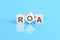 ROA - acronym from wooden blocks with letters, front view on blue background