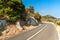 Road above the sea on the Croatian island of Lastovo. Road transport. Morning sun on the road by the sea. Asphalt road