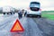 Road accident sign on the background man replaces flat tyre on road. Car tire leak because of nail pounding