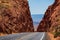 Road against the high red rocks. Barren scenery, Endless straight.