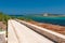 Road along the coastline in Portopalo southern Sicily; the island of `Capo Passero` in the background