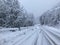 The road along a snow-covered serpentine road in the mountains during a blizzard