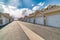 Road along white doors of attached garages of townhouses on a sunny day