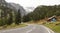 Road in the Alps turning left into a pine valley and tunnel.