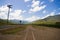 A road in Australia that is empty near cairns with the outback feeling telephone poles and a dirt road with train tracks