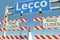 Road barricades near Lecco city road sign. Lockdown in Italy conceptual 3D rendering
