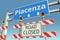 Road barricades near Piacenza city road sign. Lockdown in Italy conceptual 3D rendering