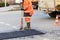 A road builder collects fresh asphalt on part of the road and levels it for repair in road construction