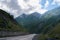 Road built in highland with giant rocky mountains and slopes covered in haze in sunny weather