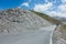 Road at Col Agnel mountain pass between France and Italy along a mountain with loose rocks