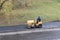 Road construction worker compactes fresh steaming asphalt with roller compactor machine