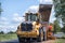 Road construction workers repairing highway road on sunny summer day