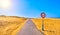 A road crossing an arid dune terrain with a No overtaking sign