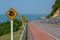 Road curve with caution signs and blue sea background Chanthaburi Thailand.