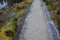 Road cut into the slope. above and below the road is a stone dry wall. nature trail through the autumn park with a drain and a met