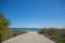 Road ending in sandy beach and blue water with clear sky on a summer day in Spain