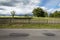 Road fence, meadow with trees and clouds