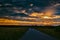 Road in the field at sunset. Summer field. Asphalt road. Summer landscape. Russian roads