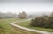 Road in the fields on a foggy morning. The village landscape.