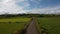 A road between fields in Ireland. Blue sky over grass fields. Irish summer landscape. Green grass field under blue sky