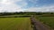 A road between fields, Ireland. Blue sky over grass fields. Irish summer landscape. Green grass field under blue sky