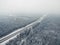 Road in the frozen winter forest with driving cars. Foggy vanishing point perspective. Aerial