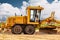 Road grader at the construction site. Powerful construction machine for ground leveling and excavation. Close-up. Professional