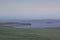 Road in green foggy grassy steppes against the background of Lake Baikal, hills and mountains in the mist, morning