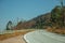 Road through hilly landscape with dry bushes and trees