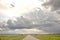 Road in Holland countryside, perspective, under heavy dark threatening cloudy skies and between meadows and a faraway straight