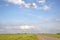 Road in Holland with red cycle path on both sides, perspective, cloudy sky and a faraway straight horizon