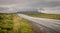 A road leading into the distance with the old man of storr in the background, silhouetted. gray, grey clouds gathering around the