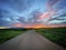 Road leading off into the distance through grassland. Beautiful sunset monsoon sky