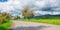 road leads through an idyllic countryside of blooming trees and vast fields