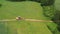 Road leveling motor grader on bad farmland road at work, aerial