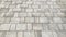 The road is made of grey stone bricks. Concrete blocks pavement. Gray square paving.