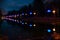 The road in the night park with illuminated umbrellas and the reflection in the river. Illumination of a park road with small