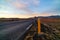 Road number one with a kilometer pole in the foreground in Iceland with snow-capped mountains in the background.