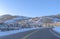 Road in Park City passing along snowed in mountain slopes with homes and trees