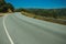 Road passing through hilly landscape with wind turbines