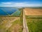 Road passing between plowed field and water treatment plant.