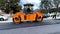 Road paving crew moving steam roller pan