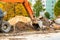 Road repair on a city street, an excavator bucket rakes in the ground, close-up