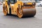 A road roller compacts fresh asphalt on the roadway on a city street