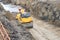 Road roller compacts the sand in a deep trench