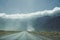 Road running into mountains with low clouds